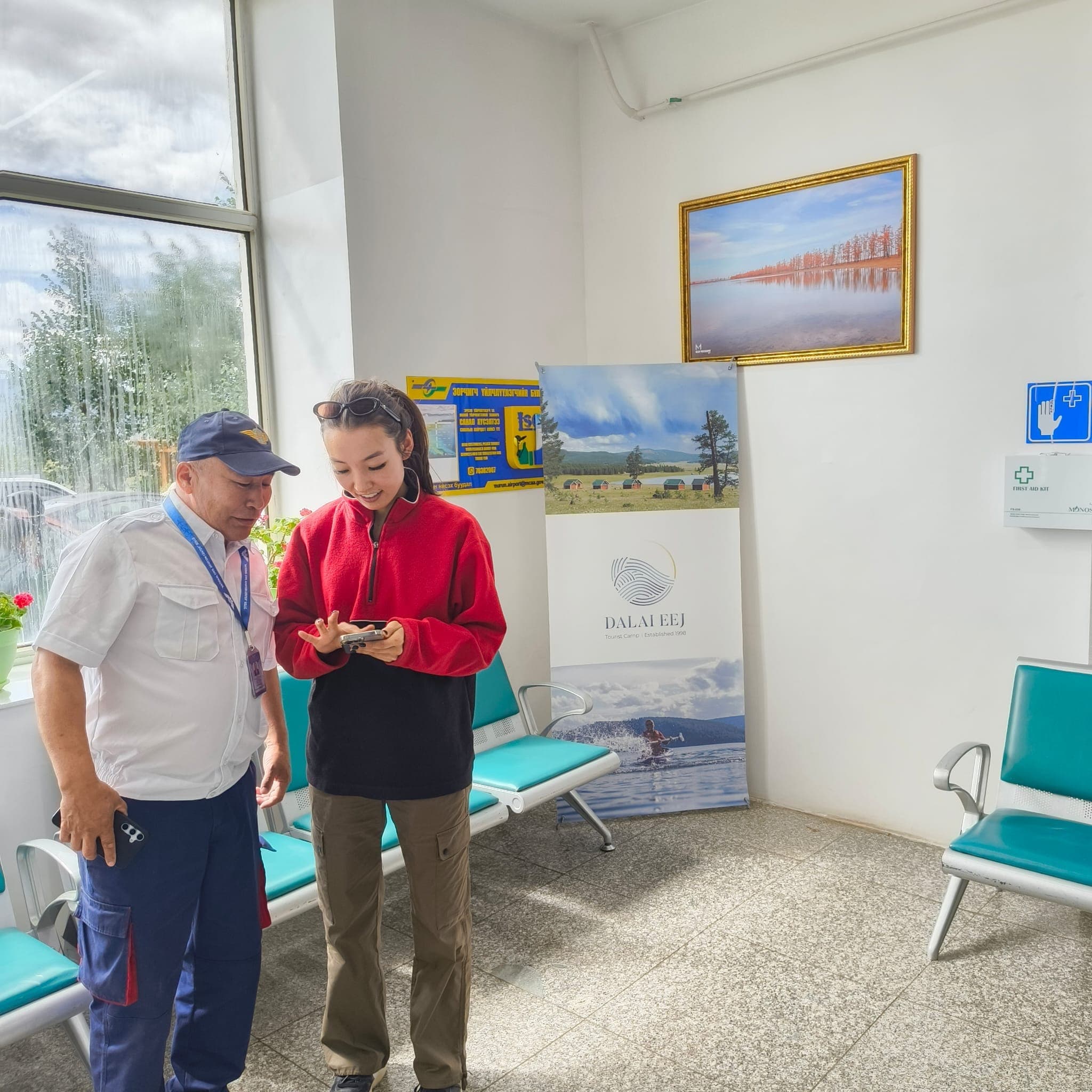 Travellers in the Murun Airport terminal with Dalai Eej Resort signage visible.